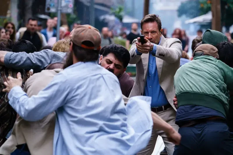the bricklayer: Aaron Eckhart inmitten einer Menschenmenge mit Pistole