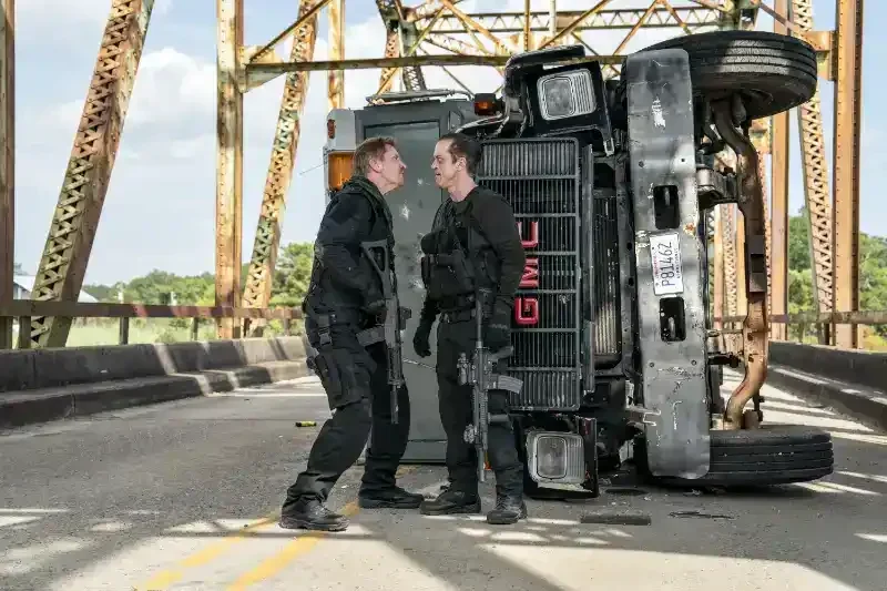 Armor Filmszene zwei männer mit waffen streiten vor umgefallenen Geldtransporter auf einer Brücke