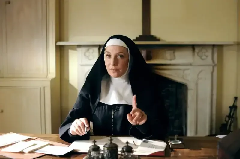 Grantchester Staffel 5 Szene: Nonne am Schreibtisch vor Kamin gestikuliert ernst.
