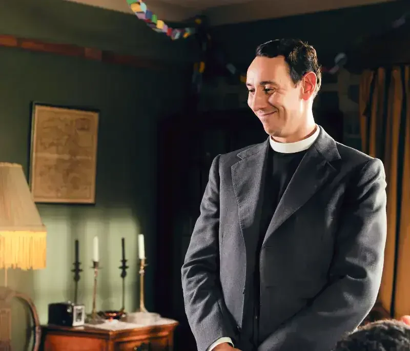 Grantchester Staffel 5 Szene: Priester lächelt in gemütlichem Raum