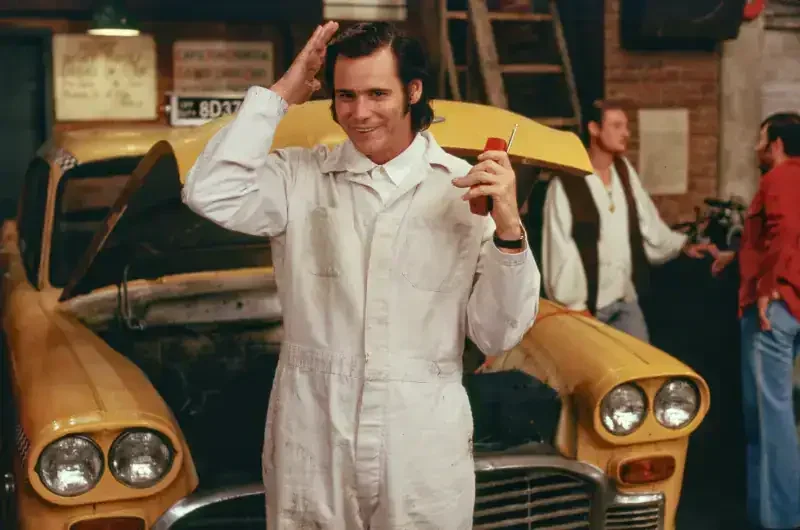 Der Mondmann Filmszene: Mechaniker mit Kamm vor gelbem Taxi
