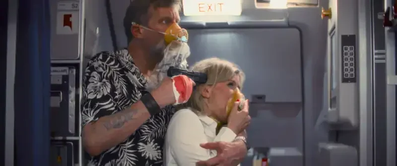 Monster on a Plane Filmszene: Mann hält Frau mit Pistole in Flugzeug fest.