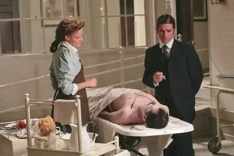 Murdoch Mysteries Staffel 1 Szenenbild: eine Pathologin und ein Inspektor mit Leiche auf Tisch.