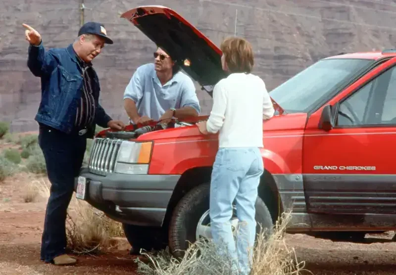 Breakdown Filmzene: Drei Personen reparieren einen Jeep im Freien.