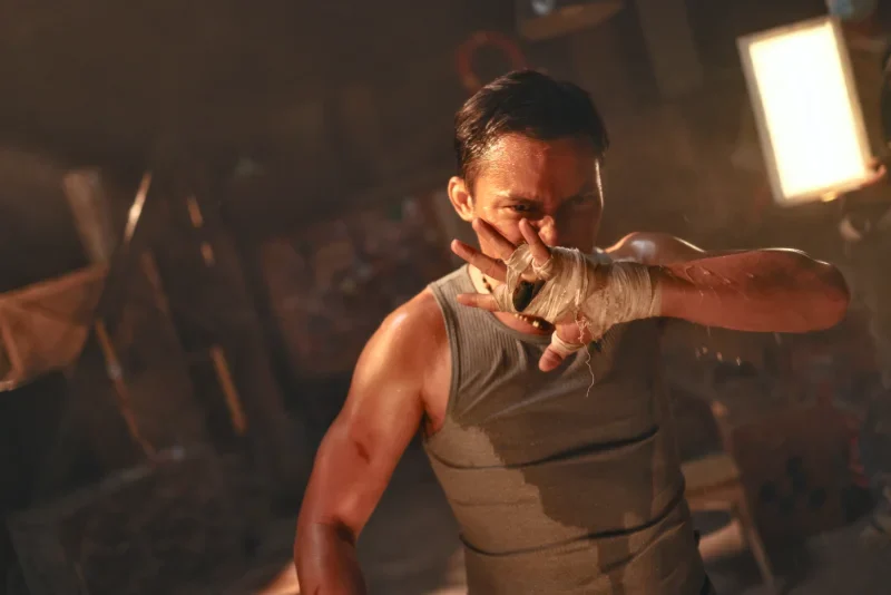 Fist of the Warrior Filmszene: Mann im Boxtraining, erhobene Hand, intensive Beleuchtung