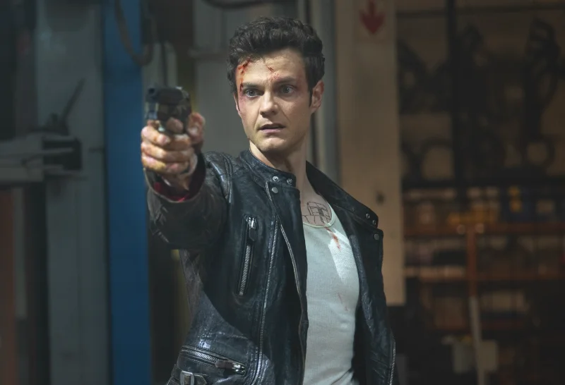Mr. No Pain - Novocaine - Filmszene: Mann in Lederjacke hält Pistole zielt.