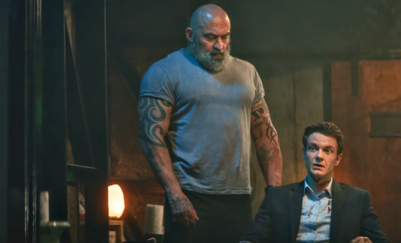 Mr. No Pain - Novocaine - Filmszene: sehr muskulöser Mann steht neben sitzenden Mann