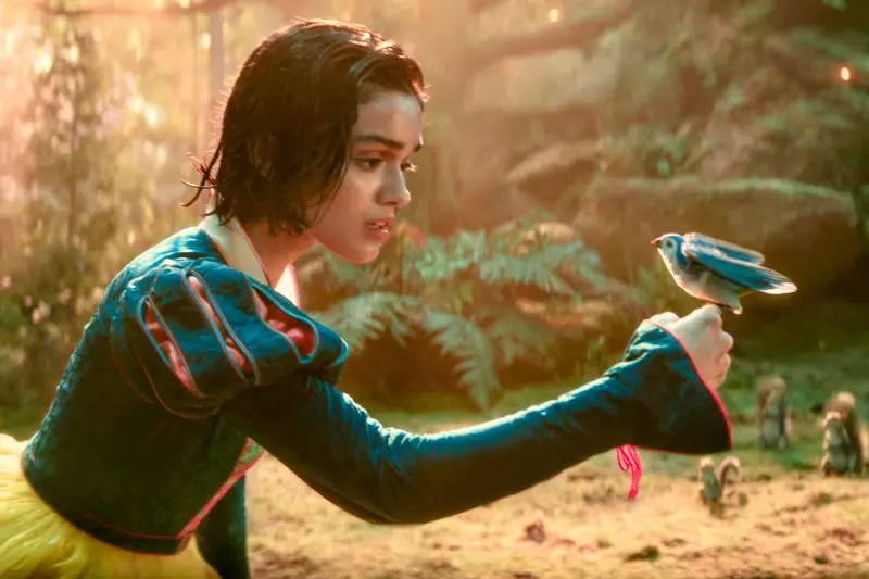 Schneewittchen 2025 Filmszene: Person hält Vogel in Waldszenario.