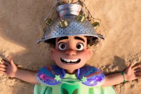 Titelheld Elio liegt mit Eigenbaufunkhelm im Sand am Strand