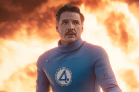 Ein Mann mit einem blauen Superhelden Kostüm steht vor einem Feuerball