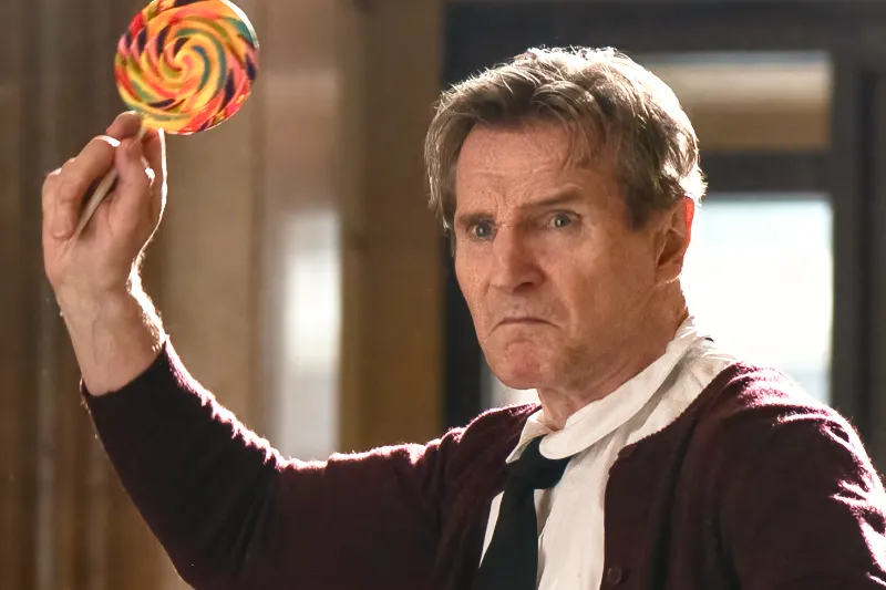 Liam Neeson als Frank Drebin jr. in Schulmädchen Uniform und Lolli - Banküberfallszene aus die nackte Kanone 2025