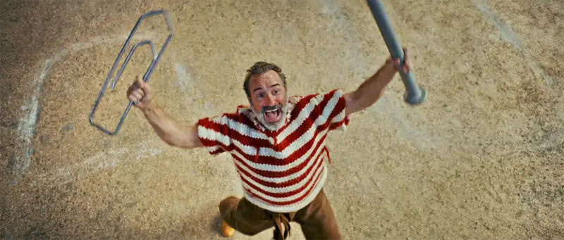 Ein winziger Mann (Jean Dujardin) mit Bürklammer, gestreifen Pulli und Nagel steht rufen da - Filmszene - Der Mann der immer kleiner wurde