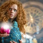 Rothaariges Mädchen (Alexa Goodall) mit roter Blume und Schildkröte auf dem Arm - Szene aus Momo 2025