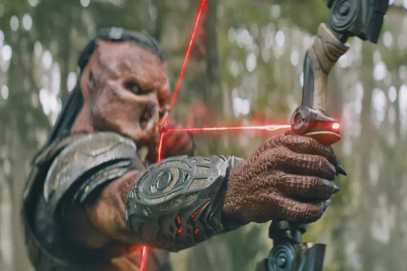 Predator Dek (Dimitrius Schuster-Koloamatangi) mit futuristischem Bogen und Laser-Visier in Predator: Badlands