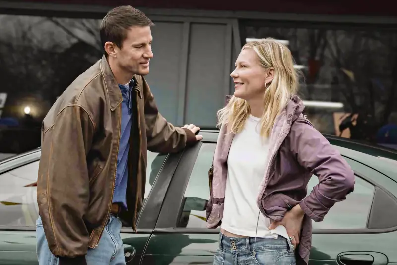 Mann (Schaupieler Channing Tatum) und Frau (Schauspielerin Kirsten Dunst) lächelnd neben Auto im Freien - Filmszene