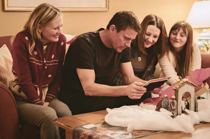 Familie betrachtet Foto neben Weihnachtskrippe im Wohnzimmer - Filmszene