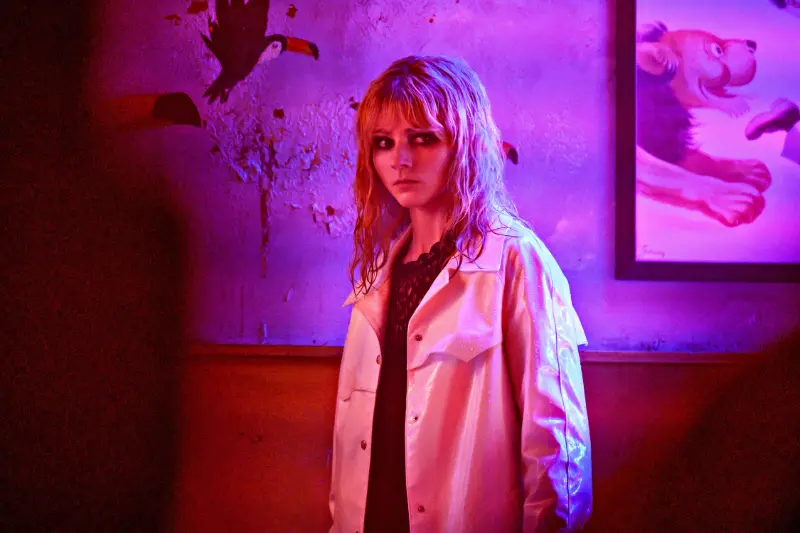 Frau (Schauspielerin Thomasin McKenzie) im Neonlicht vor Wand mit Kunstwerken - Filmszene