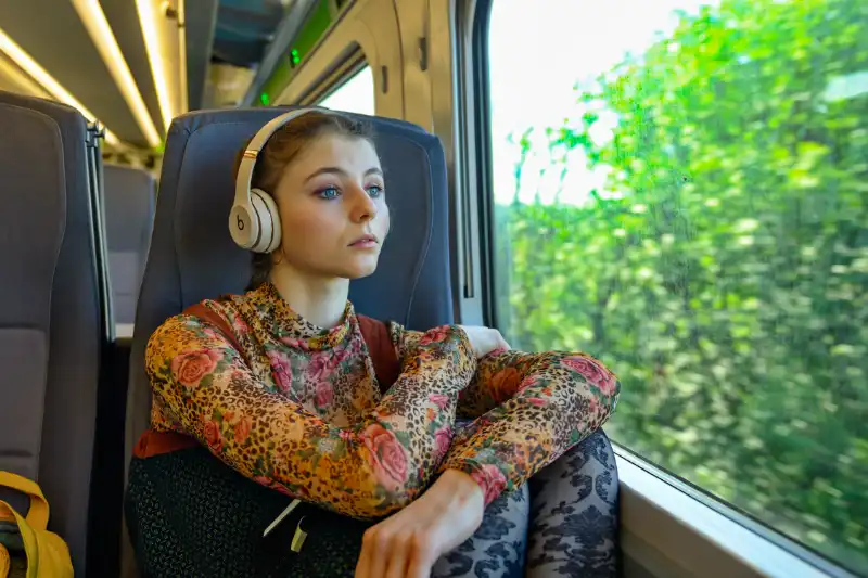 Junge Frau mit Kopfhörern im Zug am Fenster - Filmszene