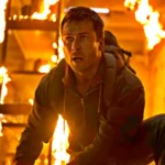 Mann kniet in brennendem Gebäude zwischen Flammen - Szene Running Man 2025