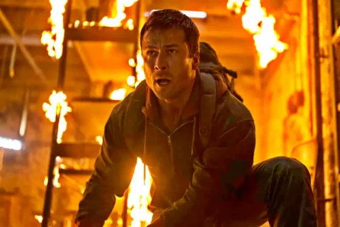 Mann kniet in brennendem Gebäude zwischen Flammen - Szene Running Man 2025