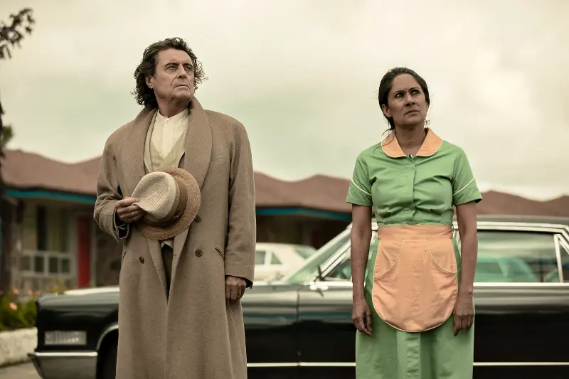 Ian McShan als Mr. Wednesday steht neben einer Frau in Kellnerin Kleidung aus American Gods