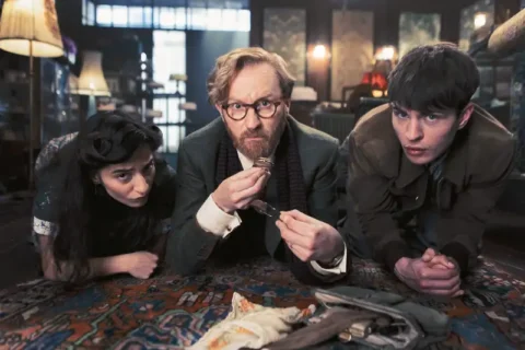 Drei Schauspieler liegen auf Teppich in düsterer Szene aus der TV-Serie Bookish