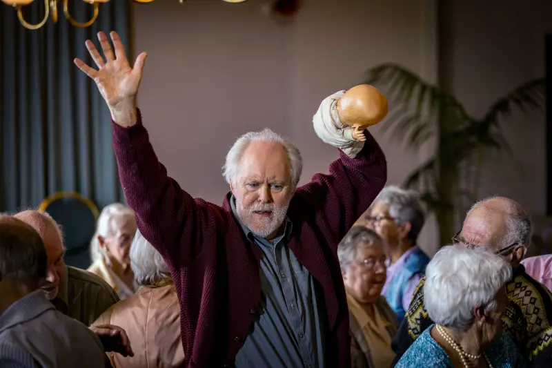 John Lithgow als Dave Crealy tanzt inmitten von Rentnern - Szene aus The Rule of Jenny Pen