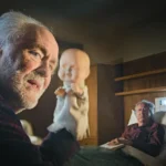 John Lithgow als Dave Crealy mit Handpuppe sitzt vor Geoffrey Rush - Szene aus The Rule of Jenny Pen