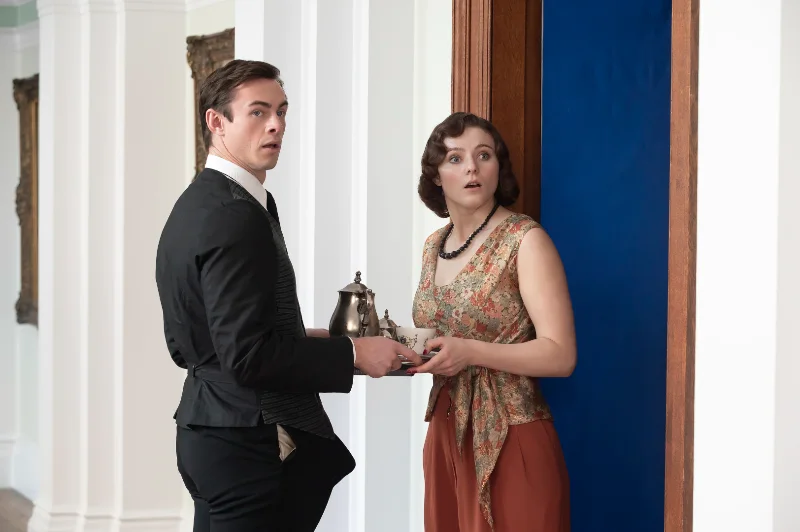 Mann im Anzug und Frau im Vintage-Kleid halten Teekanne