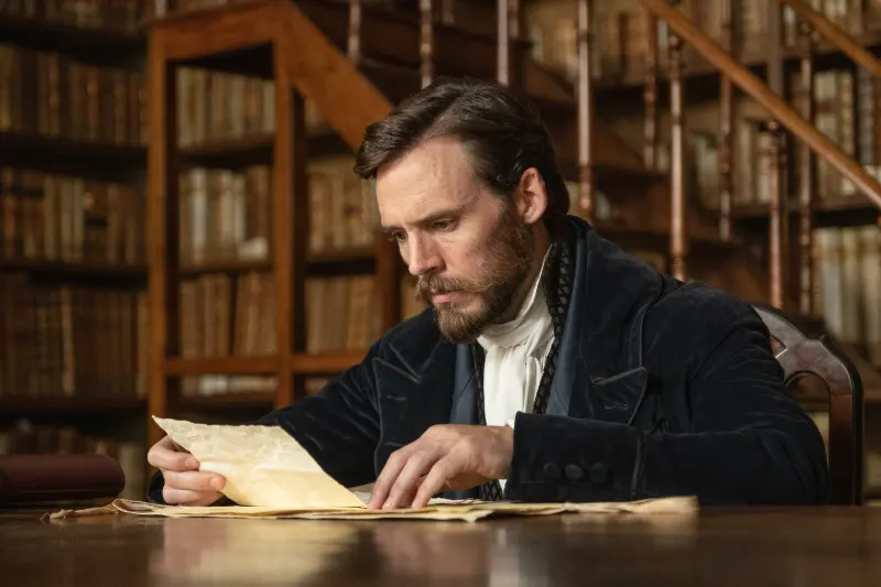 Mann in historischer Kleidung liest Dokument in alter Bibliothek