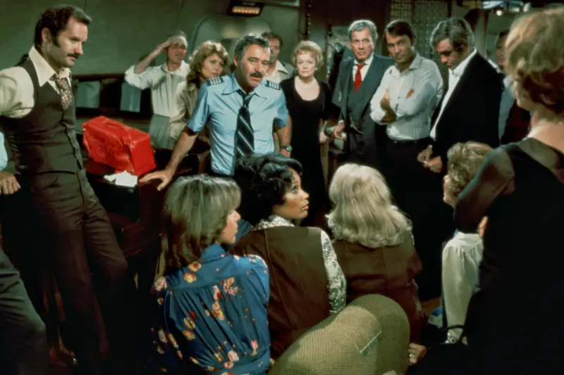 Menschenmenge in einer Flugzeugkabine, Filmszene aus den 1970er Jahren.