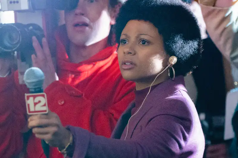 Journalistin mit Afro-Frisur hält ein Mikrofon von Kanal 12.