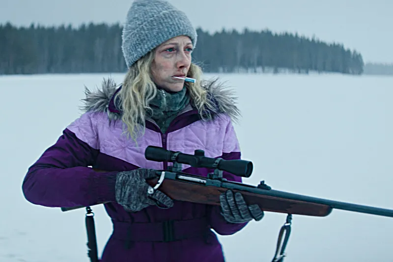 Frau mit Gewehr in einer verschneiten Winterlandschaft