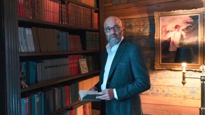 Mann mit Bart und Brille liest Buch in Bibliothek.