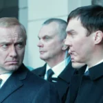 Männer in Anzügen, wobei einer Vladimir Putin stark ähnelt.