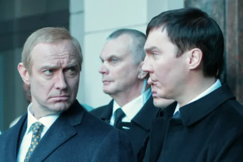 Männer in Anzügen, wobei einer Vladimir Putin stark ähnelt.