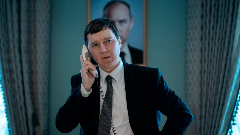 Mann im Anzug telefoniert vor einem Porträt im Hintergrund.