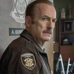 Bob Odenkirk als Sheriff Ulysses in Uniform im Büro – Szene aus dem Film Normal