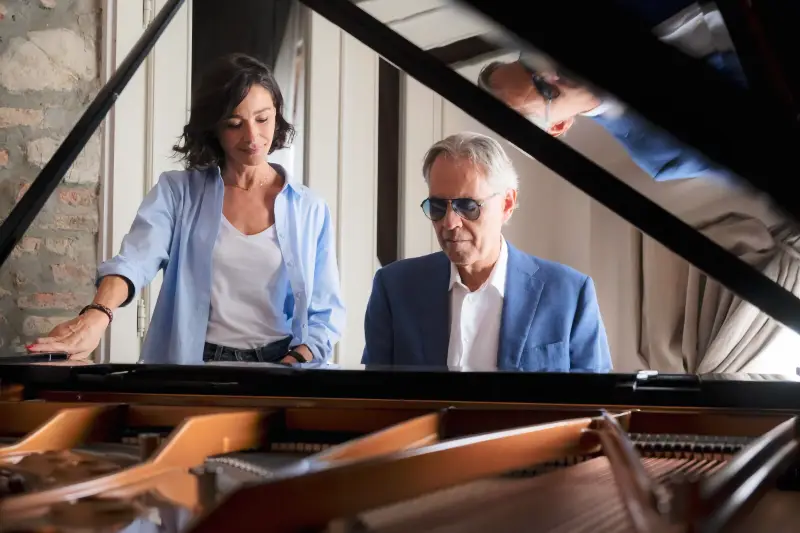 Andrea Bocelli spielt Flügel, Frau schaut ihm dabei zu