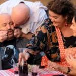 Schauspieler Kevin James als Matt mit drei Personen an einem Tisch mit Rotwein - Filmszene aus Solo Mio