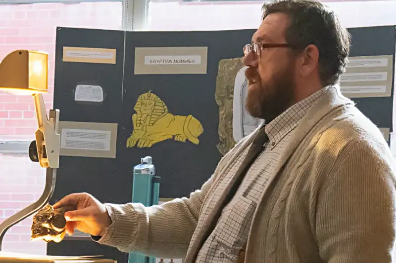 Mann präsentiert ein okkultes Objekt auf einem Tageslichtprojektor